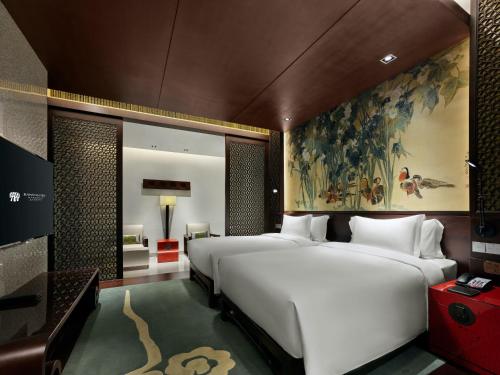 a bedroom with a large bed and a painting on the wall at Banyan Tree Hangzhou in Hangzhou