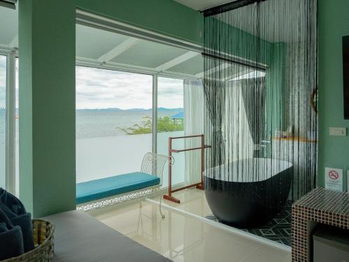 a bathroom with a large tub and a large window at Baan Sailboat Beach Kohlarn in Ko Larn