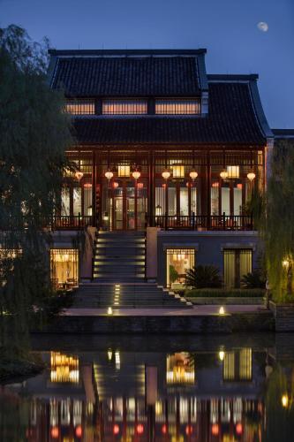 a building with lights on the water at night at Banyan Tree Hangzhou in Hangzhou