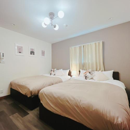 two beds in a room with white walls and wood floors at 2, Nerima, 1st floor apartment, 練馬 in Tokyo