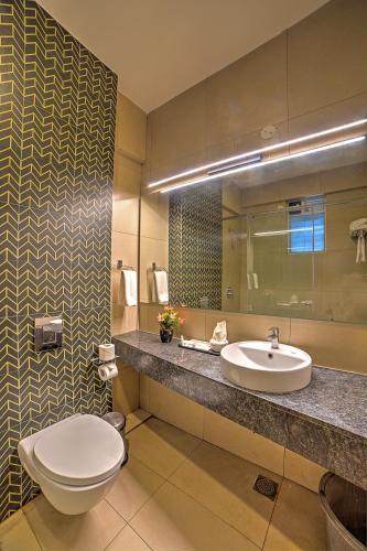 a bathroom with a toilet and a sink at VRR Astoria Hotel & Convention Center in Bangalore