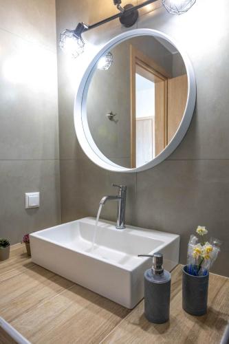 un bagno con lavandino bianco e specchio di Olive Waves apartments a Néa Péramos