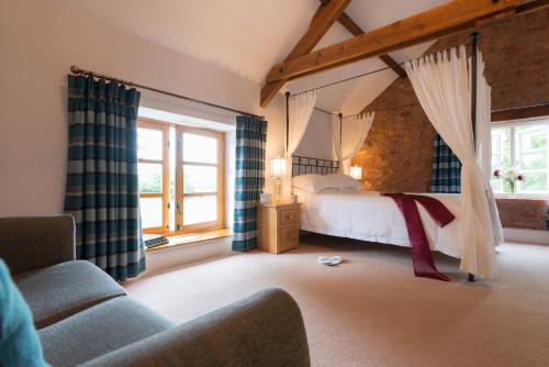 a bedroom with a bed and a couch and windows at The Old Dairy at Bishops Barton in Wellington