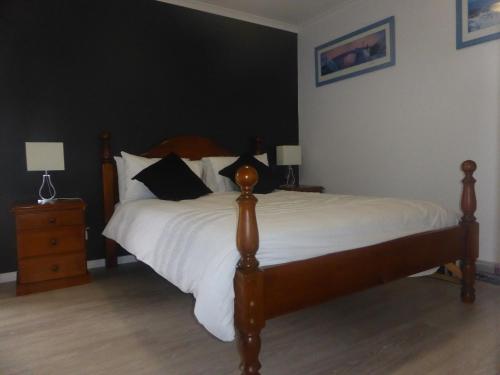 a bedroom with a bed with white sheets and black pillows at Lure Bed and Breakfast in Normanville