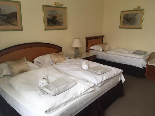 two beds in a hotel room with white sheets at Hotel Centrál in Nagykanizsa