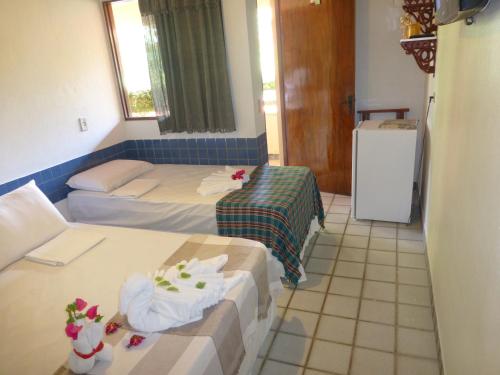 a small room with two beds and a refrigerator at Pousada das Bromélias in Porto De Galinhas