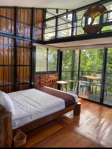a bedroom with a bed in a room with windows at My Honey's Farm in Nangkaan