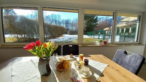 a dining room table with a vase of flowers on it at Luxus Terrassenappartement Berg & See 2 in Bodensdorf