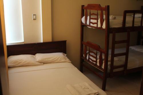 a room with a bed and a bunk bed with a ladder at Hostal Rosa Mar in Manta