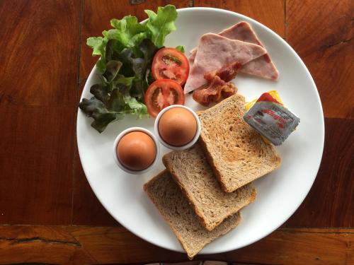 a plate of food with sandwiches and eggs on a table at Khao Sok Morning Mist Resort in Khao Sok