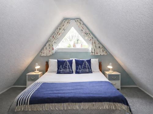 a bedroom with a bed with blue sheets and a window at Chalet 58 - The Beach House in Deal
