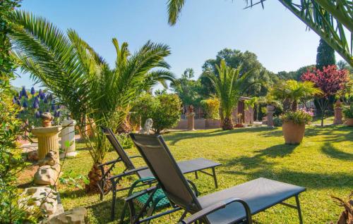 two chairs and a table in a yard with palm trees at Silencio in Cala Ratjada