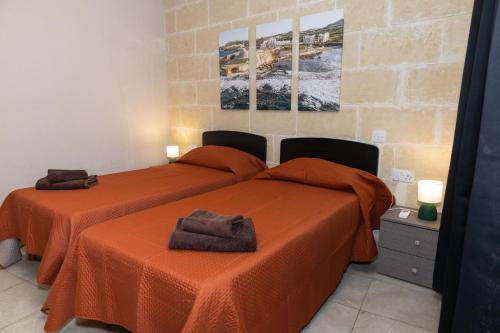 two beds in a room with orange sheets at Ta Marija in Żebbuġ