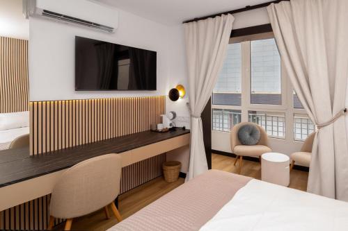 a hotel room with a bed and a desk and window at Boutique Centro Hostal in Alicante