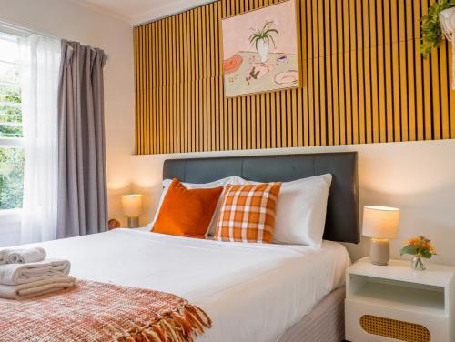 a bedroom with a bed with orange and white pillows at Train, Zoo & Eden Park Nearby - Arcade, Disney Plus- Free Parkings- Central & Peaceful in Auckland