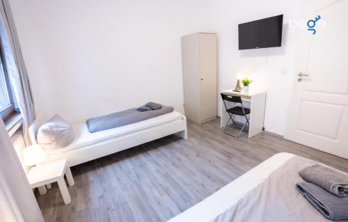 a bedroom with a bed and a desk and a tv at BEGE APARTMENTS DowntownFlat in Niederdorla