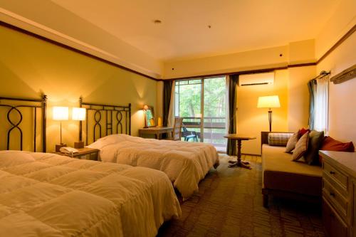 a hotel room with two beds and a couch at Kusatsu Onsen Hotel Village in Kusatsu
