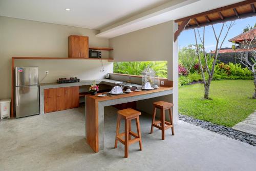 a kitchen with a counter with a refrigerator and stools at Sativa Villas Ubud with Private Pool in Ubud