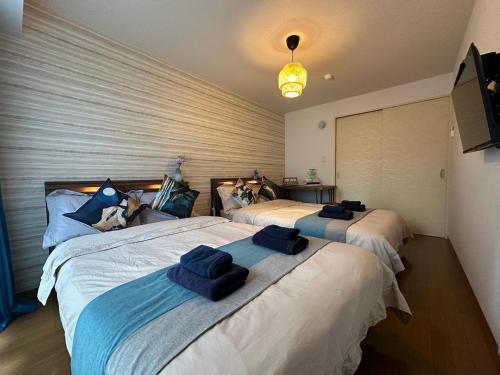 a bedroom with two beds with blue towels on them at nestay apartment tokyo shinjuku in Tokyo