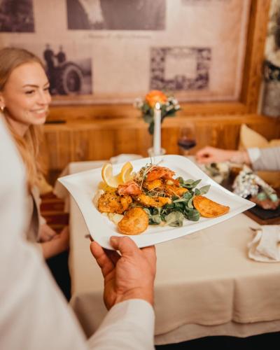 a man holding a plate of food with a woman at Panorama Hotel Leidingerhof in Mondsee