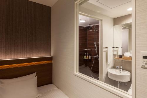a bathroom with a sink and a shower with a mirror at Nishitetsu Hotel Croom Hakata in Fukuoka