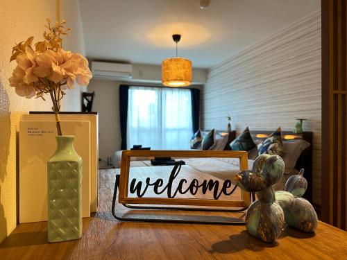 a welcome sign on a table with a vase and flowers at nestay apartment tokyo shinjuku in Tokyo