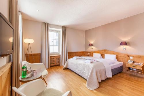 a bedroom with a bed and a table and chairs at Hotel Rosatsch in Pontresina