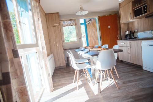 a kitchen with a table and white chairs in it at Camping Base de Loisirs du Lac de la Moselotte in Saulxures-sur-Moselotte