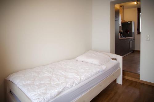 a white bed in a room with a kitchen at Ferienwohnungen Alte Molkerei in Kläden