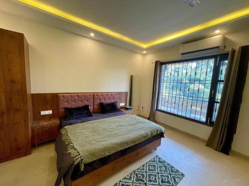 a bedroom with a large bed and a large window at Basera by the Woods in Dehradun