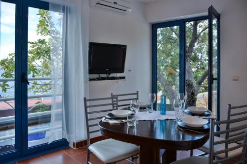 a dining room with a table and chairs and a tv at Apartments Miki in Donja Klada
