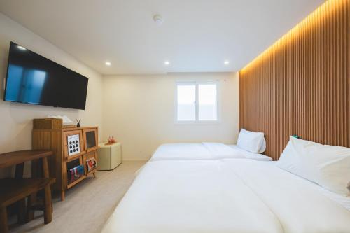 a bedroom with two beds and a flat screen tv at DadamHotel in Suwon