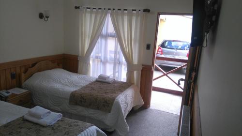a bedroom with two beds and a door to a parking lot at Hostal Loreto Belen in Puerto Natales