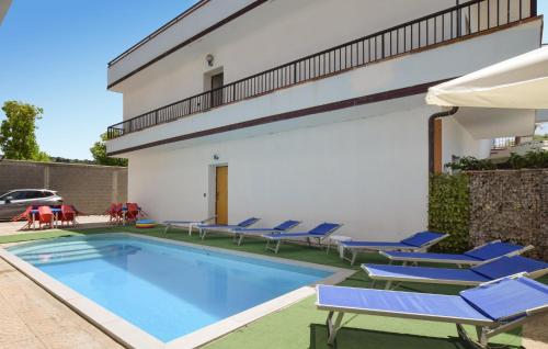 a swimming pool with blue chairs and a building at Awesome Apartment In Palmi in Palmi