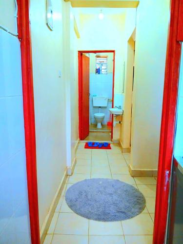a bathroom with a toilet and a rug on the floor at Ladine Homestay - Ferrum Apartment in Eldoret