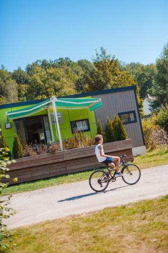 a woman riding a bike down a road at Camping Base de Loisirs du Lac de la Moselotte in Saulxures-sur-Moselotte