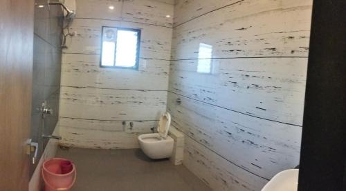 a white bathroom with a toilet and a window at Mannat Bungalow in Amrāvati