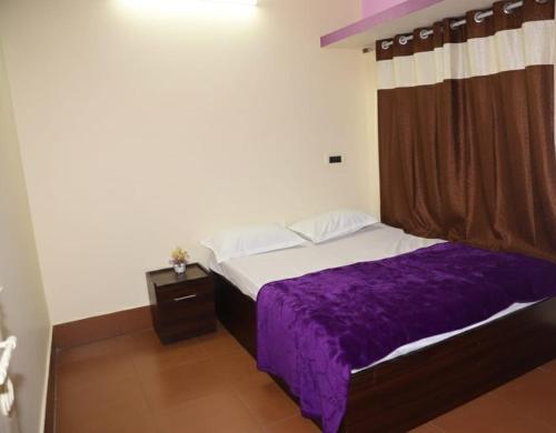 a bedroom with a bed with a purple blanket at Joyful Homestay in Mysore