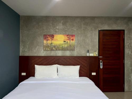 a bed in a bedroom with a painting on the wall at Easy Loft Hostel in Phuket