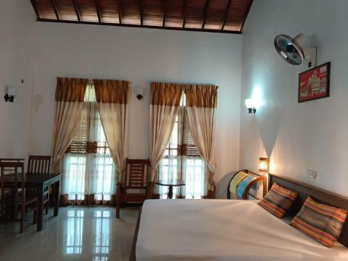 a bedroom with a bed and a table and windows at Lagoonvilla hotel in Ambalangoda