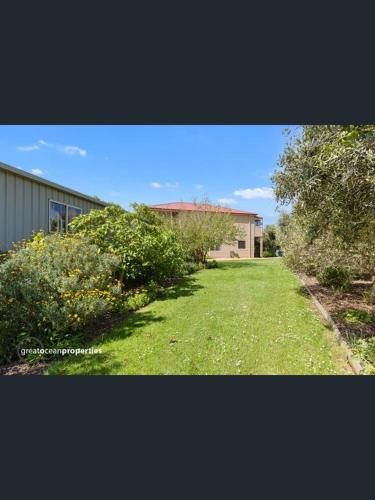 un cortile con un edificio e alcuni cespugli e alberi di Beachside Apartment a Apollo Bay