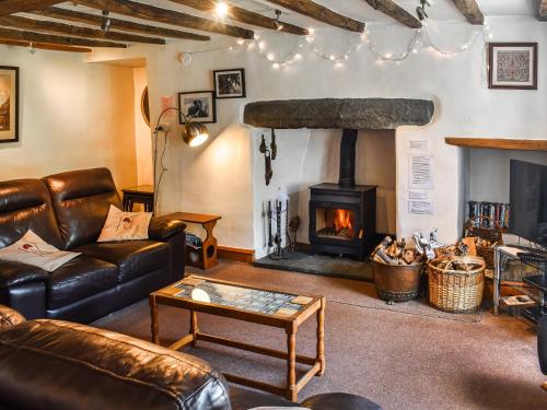 a living room with a fireplace and leather furniture at Church House in Ulpha