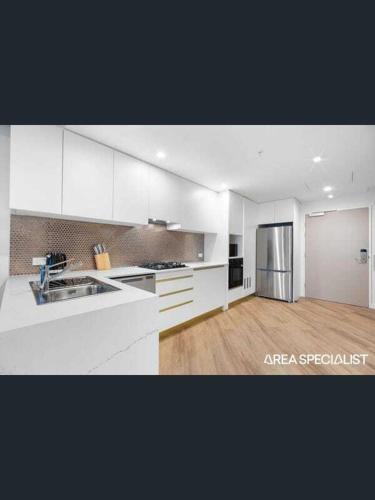 a kitchen with white cabinets and a stainless steel refrigerator at apartment in Tryp by Wyndham near broadwater in Gold Coast
