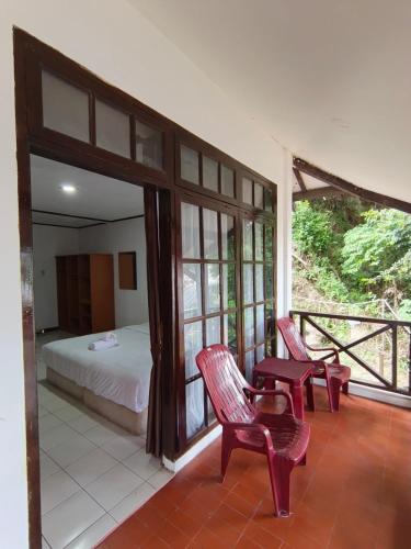 a bedroom with a bed and two chairs on a porch at Hotel Pandu Lakeside Tuktuk in Tuktuk Siadong