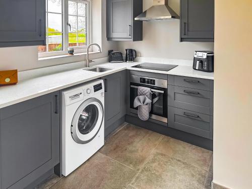 a kitchen with a washing machine and a sink at Cleveland View Cottage in North Cowton