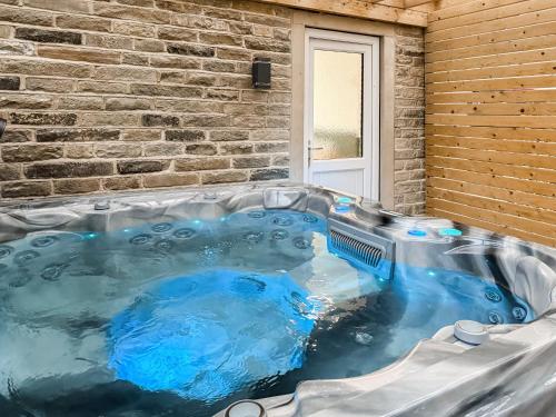 a hot tub in front of a brick wall at Wellhead Cottage in Haworth