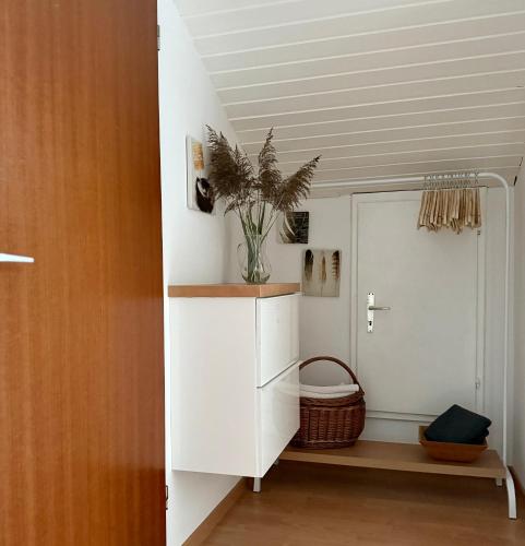 a room with a white cabinet with a vase on it at Refugium by Zirwick Apartment in Weiherhammer