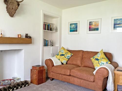 a living room with a brown couch and a fireplace at Seasgair in Dingwall