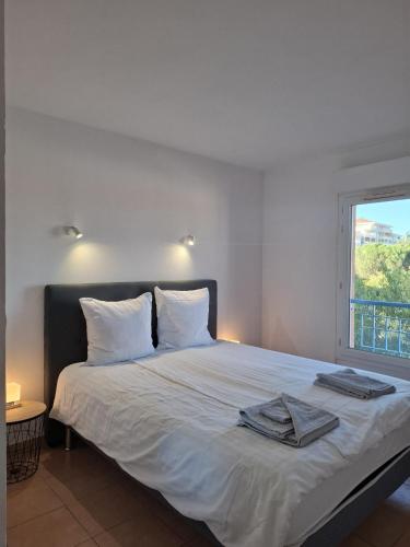 a bedroom with a bed with white sheets and a window at Appartement Riposa in Fréjus