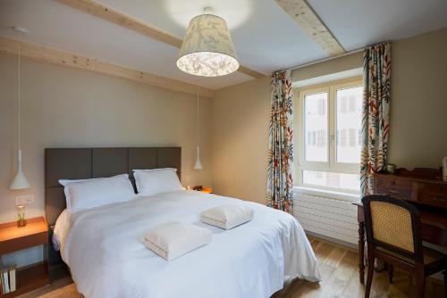 a bedroom with a large white bed and a window at Hôtel Le Bec Bed and Chocolate self check-in in Fleurier